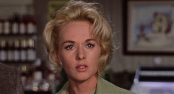Movie still from “The Birds” (1963), directed by Alfred Hitchcock – An older woman with blonde hair and a green jacket; Close Up shot, Low angle