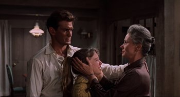 Movie still from “The Birds” (1963), directed by Alfred Hitchcock – An older woman holding a young girl's head while a young man holds her hand over her head; Medium shot, Low angle