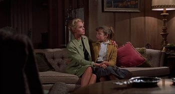 Movie still from “The Birds” (1963), directed by Alfred Hitchcock – A woman sitting on a couch with a young girl; Medium shot, Low angle