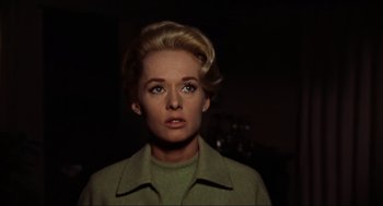 Movie still from “The Birds” (1963), directed by Alfred Hitchcock – A woman in a green jacket looking at the camera; Close Up shot, Low angle