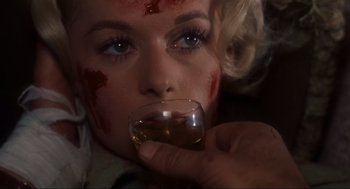 Movie still from “The Birds” (1963), directed by Alfred Hitchcock – A woman with blood all over her face drinking a glass of wine; Extreme Close Up shot, Overhead angle