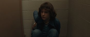 Movie still from “The Black Phone” (2021), directed by Scott Derrickson – A boy sitting on the ground in a room; Medium shot, Low angle