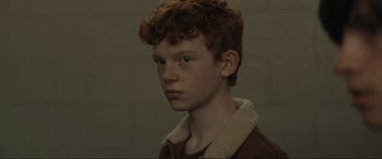 Movie still from “The Black Phone” (2021), directed by Scott Derrickson – A boy with red curly hair is looking at the camera; Close Up shot, Over the shoulder angle