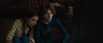 Movie still from “The Black Phone” (2021), directed by Scott Derrickson – Two young people sitting in a living room together; Medium shot, High angle