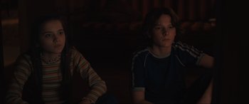 Movie still from “The Black Phone” (2021), directed by Scott Derrickson – Two young people sitting in a dark room; Medium shot, Low angle