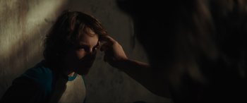 Movie still from “The Black Phone” (2021), directed by Scott Derrickson – A person touching a child's head with a finger; Close Up shot, Over the shoulder angle