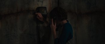 Movie still from “The Black Phone” (2021), directed by Scott Derrickson – A person holding a phone up to a wall; Close Up shot, Overhead angle
