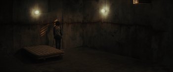 Movie still from “The Black Phone” (2021), directed by Scott Derrickson – A person standing in a room with a light hanging from the ceiling; Wide shot, High angle