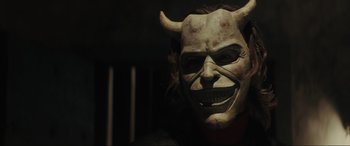 Movie still from “The Black Phone” (2021), directed by Scott Derrickson – A person wearing a devil mask in a dark room; Close Up shot, Over the shoulder angle