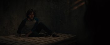 Movie still from “The Black Phone” (2021), directed by Scott Derrickson – A person sitting on a bed in a dark room; Medium shot, High angle