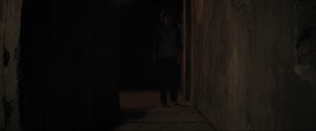 Movie still from “The Black Phone” (2021), directed by Scott Derrickson – A man standing in a dark room next to a wall; Wide shot, High angle