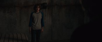Movie still from “The Black Phone” (2021), directed by Scott Derrickson – A young man standing in front of a concrete wall; Medium shot, Over the shoulder angle