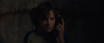 Movie still from “The Black Phone” (2021), directed by Scott Derrickson – A young man holding a cell phone up to his ear; Close Up shot, Over the shoulder angle