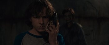 Movie still from “The Black Phone” (2021), directed by Scott Derrickson – A young man talking on a phone in a dark room; Close Up shot, Over the shoulder angle