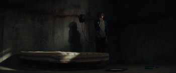 Movie still from “The Black Phone” (2021), directed by Scott Derrickson – A person standing next to a bed talking on a phone; Wide shot, High angle