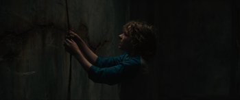 Movie still from “The Black Phone” (2021), directed by Scott Derrickson – A person in a dark room touching a wall; Medium shot, Low angle