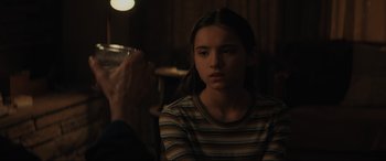 Movie still from “The Black Phone” (2021), directed by Scott Derrickson – A young girl sitting in front of a glass of water; Close Up shot, Over the shoulder angle