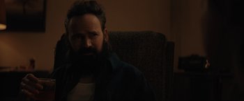 Movie still from “The Black Phone” (2021), directed by Scott Derrickson – A bearded man sitting on a couch in the dark; Close Up shot, Over the shoulder angle