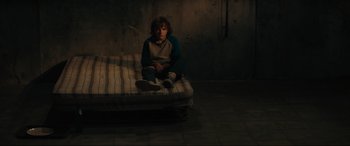 Movie still from “The Black Phone” (2021), directed by Scott Derrickson – A person sitting on a mattress in a room; Wide shot, High angle