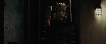 Movie still from “The Black Phone” (2021), directed by Scott Derrickson – A man in a demon mask holding a book; Medium shot, Low angle