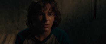 Movie still from “The Black Phone” (2021), directed by Scott Derrickson – A young man with long dark hair is looking at the camera; Close Up shot, Over the shoulder angle