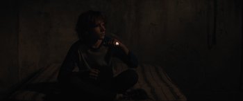 Movie still from “The Black Phone” (2021), directed by Scott Derrickson – A man sitting on the ground holding a flashlight; Medium shot, High angle