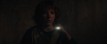 Movie still from “The Black Phone” (2021), directed by Scott Derrickson – A young boy is holding a flashlight in the dark; Close Up shot, Over the shoulder angle