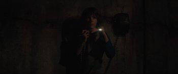 Movie still from “The Black Phone” (2021), directed by Scott Derrickson – A person holding a phone in a dark room; Medium shot, High angle