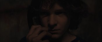 Movie still from “The Black Phone” (2021), directed by Scott Derrickson – A man with long dark hair is holding a cell phone to his face; Close Up shot, Overhead angle
