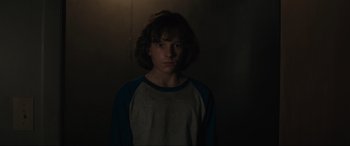 Movie still from “The Black Phone” (2021), directed by Scott Derrickson – A young boy is standing in a dark room; Close Up shot, Over the shoulder angle