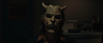 Movie still from “The Black Phone” (2021), directed by Scott Derrickson – A man wearing a demon mask in a dark room; Close Up shot, Overhead angle