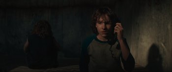 Movie still from “The Black Phone” (2021), directed by Scott Derrickson – A young man holding a phone up to his ear; Medium shot, Over the shoulder angle