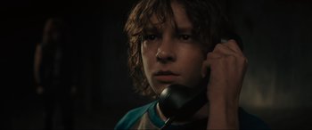 Movie still from “The Black Phone” (2021), directed by Scott Derrickson – A young man holding a phone up to his ear; Close Up shot, Low angle