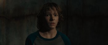 Movie still from “The Black Phone” (2021), directed by Scott Derrickson – A young man with long brown hair wearing a blue and gray t - shirt; Close Up shot, Low angle