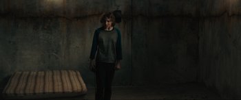 Movie still from “The Black Phone” (2021), directed by Scott Derrickson – A person standing in a room with a chair; Wide shot, High angle