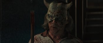 Movie still from “The Black Phone” (2021), directed by Scott Derrickson – A person with a demon mask and a sword in a dark room; Close Up shot, Low angle