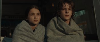 Movie still from “The Black Phone” (2021), directed by Scott Derrickson – Two young girls wrapped in a blanket looking at the camera; Medium shot, Low angle
