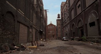 Movie still from “The Blues Brothers” (1980), directed by John Landis – An alley way with a church in the middle of it; Extreme Wide shot, High angle