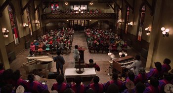 Movie still from “The Blues Brothers” (1980), directed by John Landis – A large group of people sitting in front of a stage; Extreme Wide shot, High angle