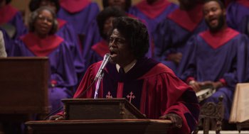 Movie still from “The Blues Brothers” (1980), directed by John Landis – An african american woman is speaking at a church; Medium shot, Low angle