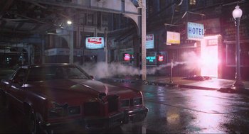 Movie still from “The Blues Brothers” (1980), directed by John Landis – A red car driving down a street next to a building; Extreme Wide shot, High angle