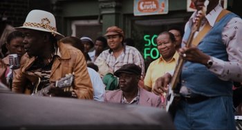 Movie still from “The Blues Brothers” (1980), directed by John Landis – A group of people that are standing in the street; Medium shot, Over the shoulder angle