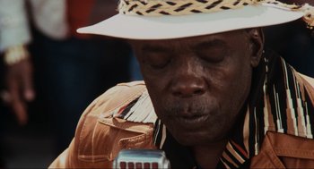 Movie still from “The Blues Brothers” (1980), directed by John Landis – A person wearing a hat and holding a cell phone; Extreme Close Up shot, Low angle