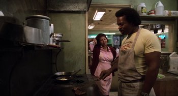 Movie still from “The Blues Brothers” (1980), directed by John Landis – A man and a woman are cooking in a kitchen; Medium shot, Low angle