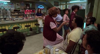 Movie still from “The Blues Brothers” (1980), directed by John Landis – A group of people standing around in a room; Medium shot, Over the shoulder angle