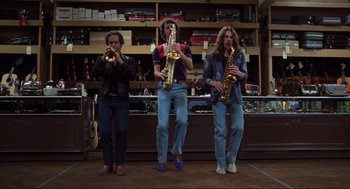 Movie still from “The Blues Brothers” (1980), directed by John Landis – A group of men standing next to each other holding saxophones; Wide shot, Low angle