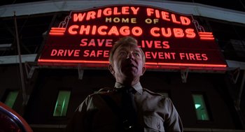 Movie still from “The Blues Brothers” (1980), directed by John Landis – A man standing in front of a wrigley field sign; Medium shot, Low angle