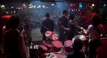 Movie still from “The Blues Brothers” (1980), directed by John Landis – A group of men playing drums in front of an audience; Wide shot, Over the shoulder angle
