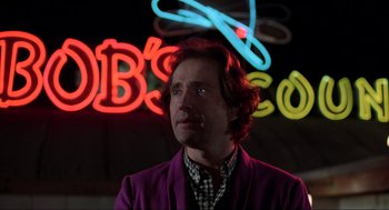 Movie still from “The Blues Brothers” (1980), directed by John Landis – A man in a purple jacket standing in front of neon signs; Close Up shot, Low angle
