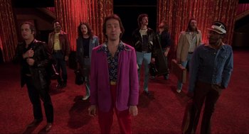 Movie still from “The Blues Brothers” (1980), directed by John Landis – A group of people standing in a red room; Wide shot, Low angle